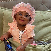 Jalayah joined the competition — help win amazing prizes! baby, bed, bodypart, bonnet, cap, clothing, couch, electronics, face, finger, furniture, hand, hat, head, mobilephone, person, phone, photography, portrait, sitting