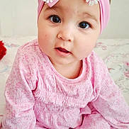 Beatrice participe au concours pour gagner de l'argent avec cette photo : baby, bed, bedspread, big_eyes, booties, bow, chubby_cheeks, cute, floral_pattern, girl, hand, headband, infant, nursery, pink_clothing, pink_headband, portrait, sitting, smile, socks