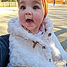 baby, big_eyes, bow, child, close_up, clothing, cute, earring, fluffy_coat, happy, headband, infant, mouth_open, outdoors, park, person, portrait, rosy_cheeks, smiling, white_coat
