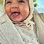 baby, infant, smiling, laughing, tongue_out, bonnet, hood, coat, sweater, dress, closeup, portrait, rosy_cheeks, chubby_cheeks, adorable, happy, earring, fabric_texture, soft_lighting, warm_clothing