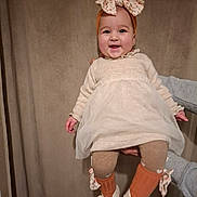 Beatrice a rejoint le concours — aidez-le/la à gagner de superbes lots ! baby, infant, smile, headband, bow, dress, tights, socks, shoes, person, hand, adult_hand, portrait, indoor, curtain, happy, cute, earrings, fashion, wall