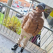 Eduard participe au concours pour gagner de l'argent avec cette photo : child, boy, glasses, cap, puffer_jacket, nike, adidas, sneakers, railing, balcony, urban, parking_lot, cars, billboard, advertisement, sidewalk, outdoor, streetwear, smile, portrait