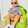 casual, child, confident, cool, fashion, footwear, green_chair, indoor, kid, nike, plush_chair, portrait, purple_clothing, short_hair, sitting, sock, spongebob, sunglasses, tile_floor, white_sneakers