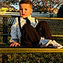 bench, black_pants, boy, casual, child, daylight, fashion, fence, grass, nike, outdoor, park, portrait, sneakers, sunlight, suspenders, tie, tree, white_shirt, young