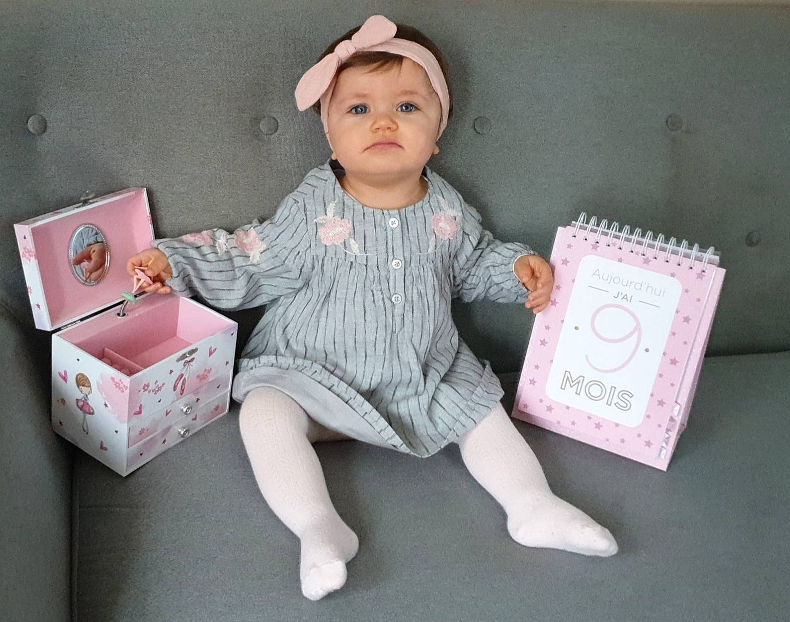 Lena participe au concours pour gagner de l'argent avec cette photo : baby_toddler_clothing, box, cap, child, craft, doll, fashion_accessory, foot, headwear, human_leg, knee, magenta, paper, paper_product, pattern, person, pink, room, sitting, sleeve