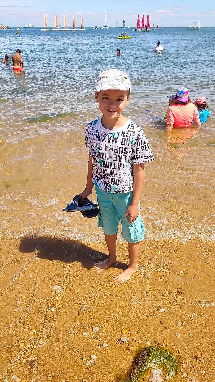 Ethan participe au concours pour gagner de l'argent avec cette photo : azure, beach, body_of_water, coastal_and_oceanic_landforms, fun, happy, hat, head, headwear, joy, leg, leisure, people_on_beach, person, sand, shorts, smile, summer, t_shirt, travel