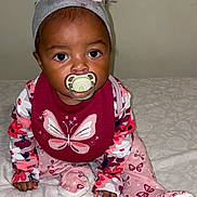 Laylani is registered to the contest to win money with this photo: baby, bib, blanket, butterfly, child, curious, cute, face, flower, foot, hand, headband, indoor, infant, maroon, pacifier, pajamas, patterned_clothing, pink, sitting