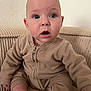Anna participe au concours pour gagner de l'argent avec cette photo : baby, child, infant, cute, surprised, beige, fleece, onesie, sitting, couch, indoor, face, expression, skin, foot, hand, young, person, portrait, cozy