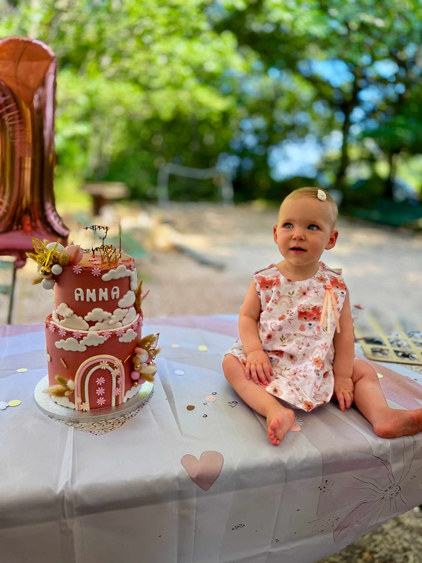 Anna participe au concours pour gagner de l'argent avec cette photo : toddler, child, birthday_cake, cake, pink, table, outdoor, nature, greenery, dress, sitting, celebration, party, decorations, face, person, summer, cute, happy, event