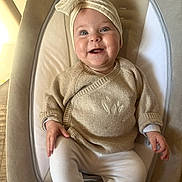 Anna participe au concours pour gagner de l'argent avec cette photo : baby, smiling, headband, bow, sweater, white_pants, baby_seat, infant, cute, happy, child, indoor, portrait, person, seat, clothing, face, hand, cozy, cushion