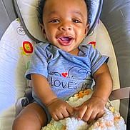 Elijah is registered to the contest to win money with this photo: baby, smiling, curly_hair, onesie, blanket, baby_seat, infant, happy, child, cute, indoor, comfort, soft_texture, toddler, portrait, cushion, person, clothing, hands, expression