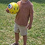 Milo a rejoint le concours — aidez-le/la à gagner de superbes lots ! ball, boy, brown_shirt, bucket_hat, bush, child, grass, greenery, nature, outdoor, person, play, sandals, shorts, smile, standing, summer, sunny, toy, yellow_ball