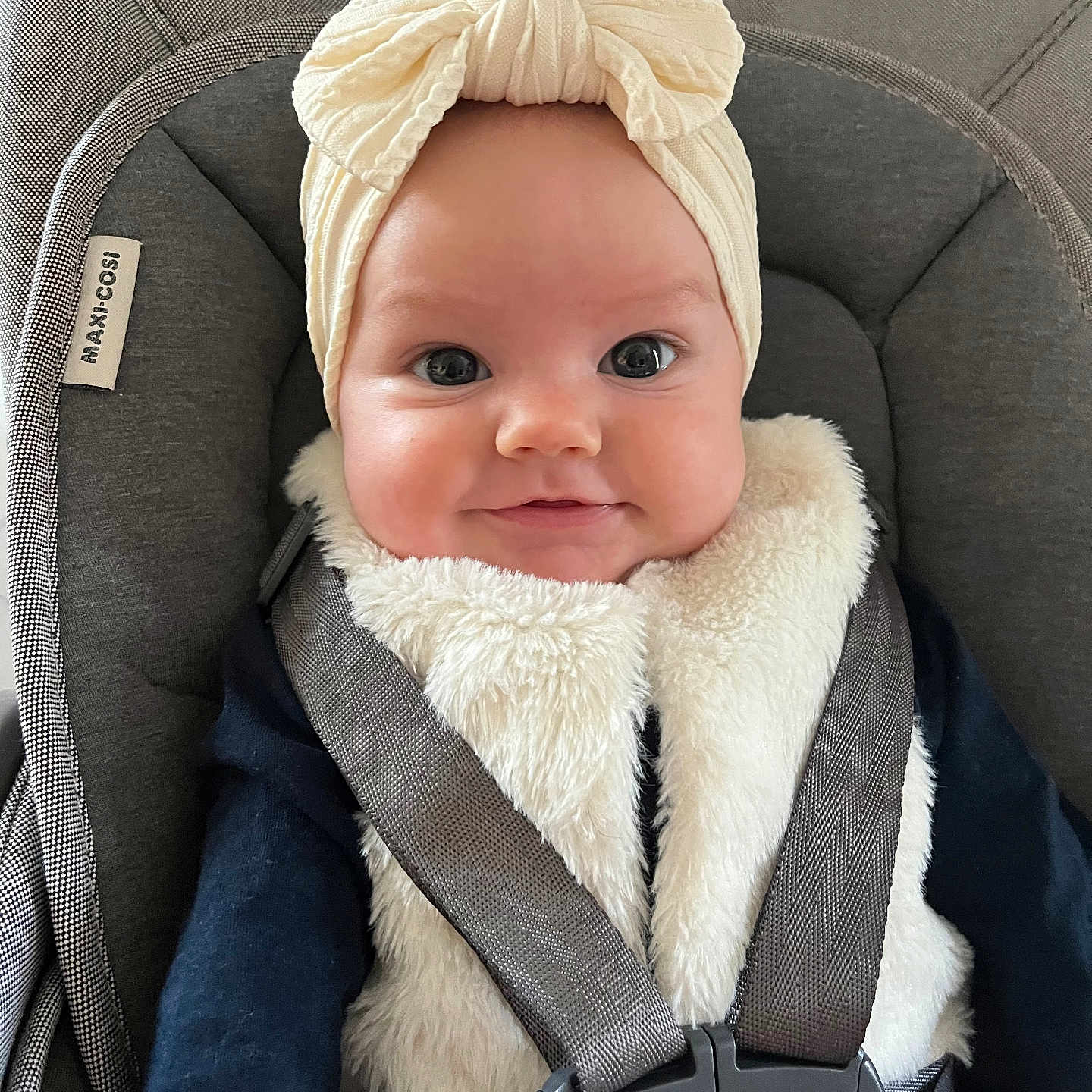 Mia participe au concours pour gagner de l'argent avec cette photo : baby, baby_fashion, car_seat, child, closeup, clothing, cute, face, happy, head_wrap, indoors, infant, person, portrait, safety, seat, smile, soft_texture, straps, vest