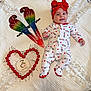 baby, infant, onesie, headband, red_bow, smile, face, parrot_decor, cherries, heart_shape, wooden_plaque, 7_months, white_blanket, texture, milestone, cute, lying_down, happy, celebration, indoors