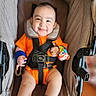 Bodoquito is registered to the contest to win money with this photo: baby, smiling, stroller, orange_clothing, blue_socks, wrist_rattle, child, infant, seatbelt, safety_harness, happy, portrait, indoors, cushion, head_support, cute, person, baby_accessory, colorful, seated