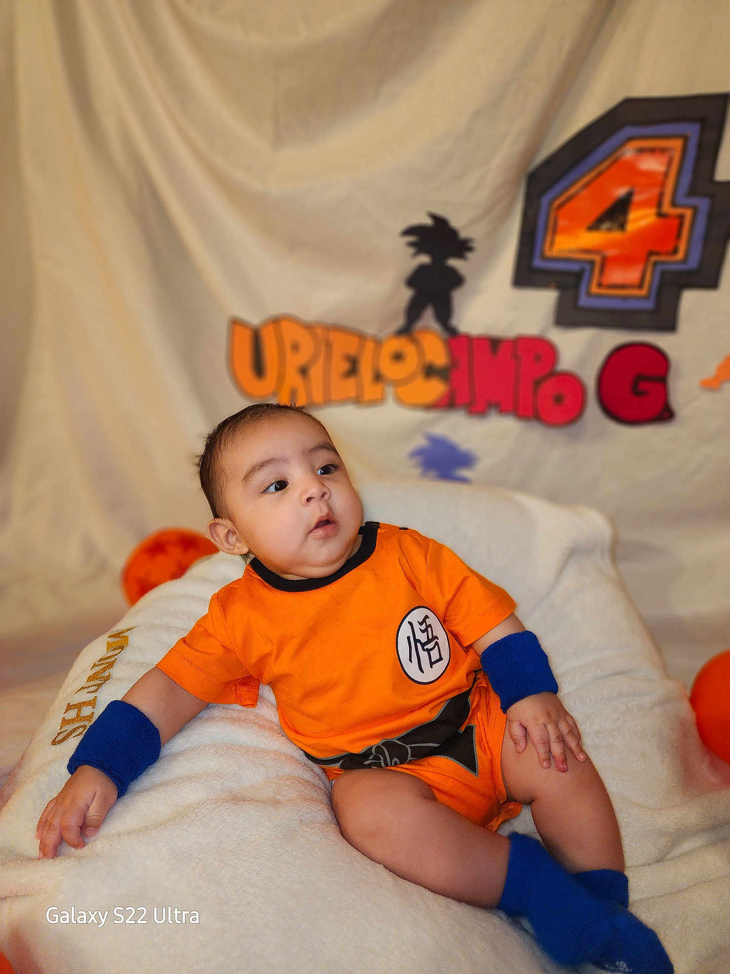 Bodoquito joined the competition — help win amazing prizes! baby, backdrop, birthday_decoration, blanket, blue_socks, blue_wristband, child, cute, decorative_letters, dragon_ball, gaze, goku_silhouette, infant, number_4, orange_outfit, plush, portrait, sitting, studio_lighting, watermark