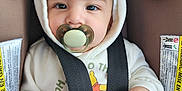 Bodoquito joined the competition — help win amazing prizes! baby, infant, child, pacifier, car_seat, seat_belt, harness, hood, hooded_outfit, blanket, hand, face, eyes, closeup, portrait, cute, onesie, warning_label, camera_watermark, soft_lighting