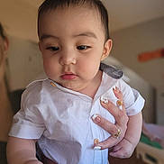 Bodoquito is registered to the contest to win money with this photo: baby, child, infant, white_shirt, hand, manicure, nails, indoor, portrait, curious, soft_lighting, face, skin, cute, young_child, person, holding, close_up, furniture, room
