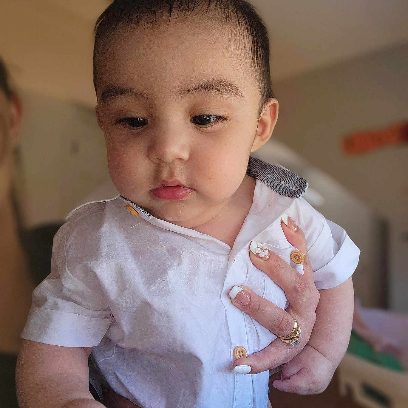 Bodoquito is registered to the contest to win money with this photo: baby, child, infant, white_shirt, hand, manicure, nails, indoor, portrait, curious, soft_lighting, face, skin, cute, young_child, person, holding, close_up, furniture, room