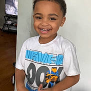 O Marius is registered to the contest to win money with this photo: child, smiling, indoor, wooden_floor, shorts, tshirt, video_call, adult, happy, person, casual_clothing, technology, home, portrait, standing, face, expression, communication, family, connection