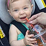 baby, child, car_seat, headband, pink, blue_eyes, smiling, drink, straw, hand, nail_polish, green_clothing, seatbelt, infant, closeup, happy, person, portrait, cute, indoor
