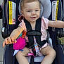 baby, car_seat, child, infant, smiling, toy, plush, safety_harness, pink_clothing, happy, cute, outdoor, seat, straps, pacifier, warning_label, person, young_child, legs, arms