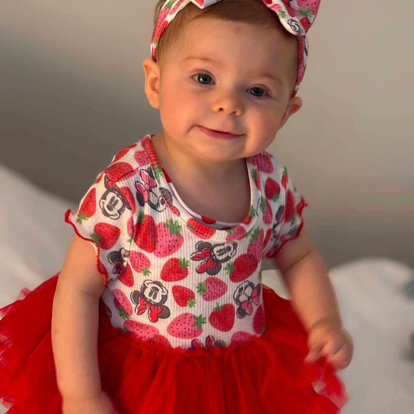 Aubri is registered to the contest to win money with this photo: baby, background, bed, child, clothing, cute, fashion, girl, happy, headband, indoor, infant, minnie_mouse, person, portrait, red_tutu, smile, soft_lighting, strawberry, tutu_skirt