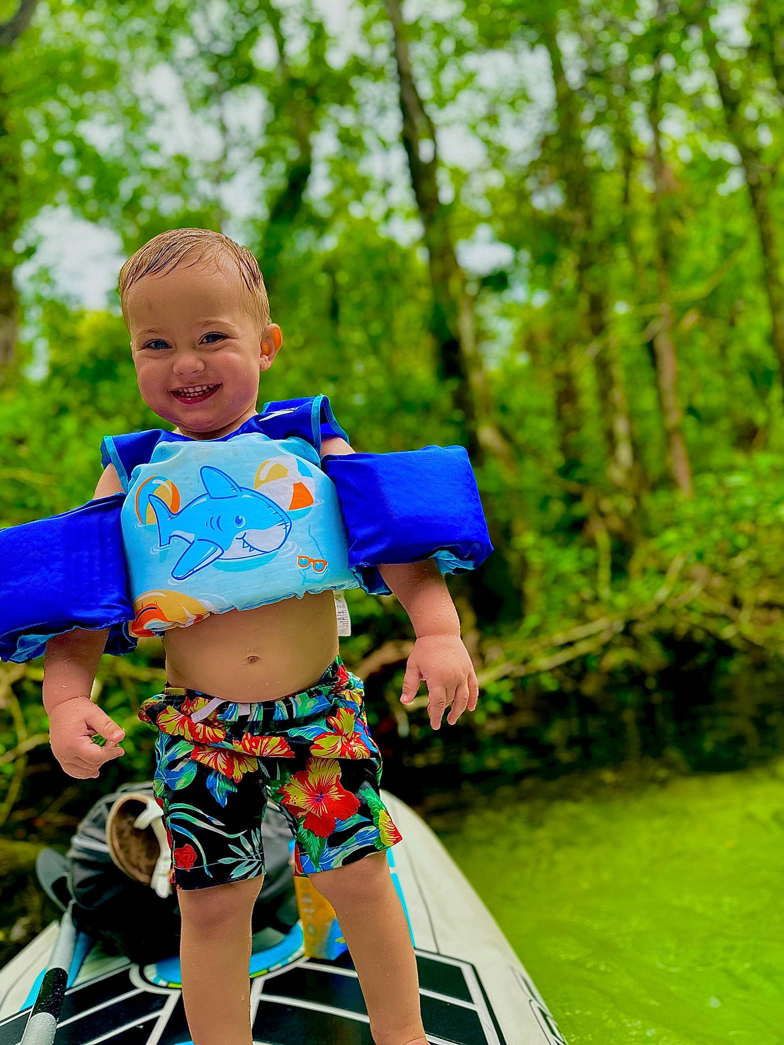Wolfe is registered to the contest to win money with this photo: abdomen, boats_and_boating_equipment_and_supplies, denim, electric_blue, fun, grass, happy, joy, leisure, people_in_nature, person, plant, recreation, shorts, sitting, smile, thigh, toddler, tree, trunk