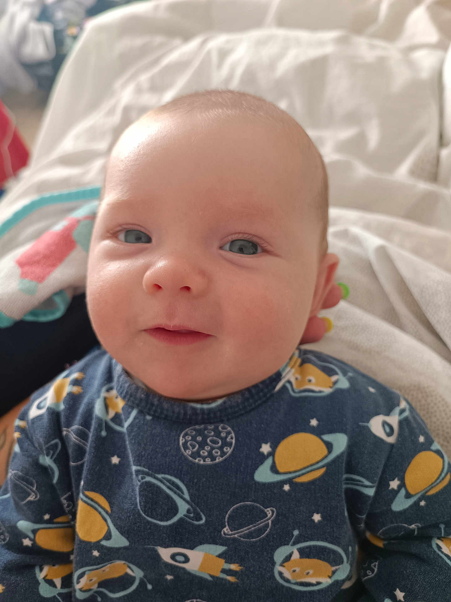 Aydenn participe au concours pour gagner de l'argent avec cette photo : baby, infant, face, smile, blue_eyes, space_theme, clothing, planets, rocket, blanket, towel, indoors, cute, child, portrait, head, young, soft_light, closeup, happy