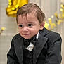 bow_tie, boy, celebration, child, curly_hair, cute, event, expression, face, fashion, festive, formal_wear, indoor, party, person, portrait, smile, toddler, tuxedo, young_child