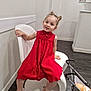 Gabriela a rejoint le concours — aidez-le/la à gagner de superbes lots ! chair, child, cute, doll, floor, footwear, girl, hairstyle, happy, home_interior, indoor, modern_chair, person, playful, red_dress, sandals, smiling, toy_stroller, wall, young_child