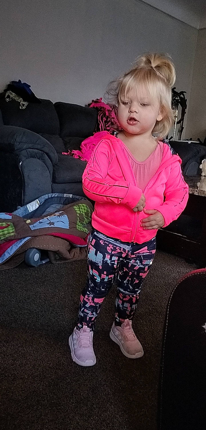 Raelynn is registered to the contest to win money with this photo: baby_toddler_clothing, blond, cheek, child, comfort, cool, happy, human_leg, knee, magenta, pattern, person, pink, shoe, sitting, sleeve, sneakers, sock, t_shirt, thigh