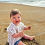 baby, child, sand, beach, ocean, water, waves, smiling, happy, sitting, clothing, shorts, shirt, barefoot, sunlight, sky, clouds, nature, outdoor, portrait