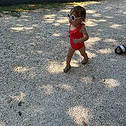 Mia participe au concours pour gagner de l'argent avec cette photo : toddler, child, sunglasses, swimsuit, walking, outdoor, gravel, shadow, sunlight, footwear, sandal, person, summer, fashion, cute, playful, sunny, nature, casual, portrait