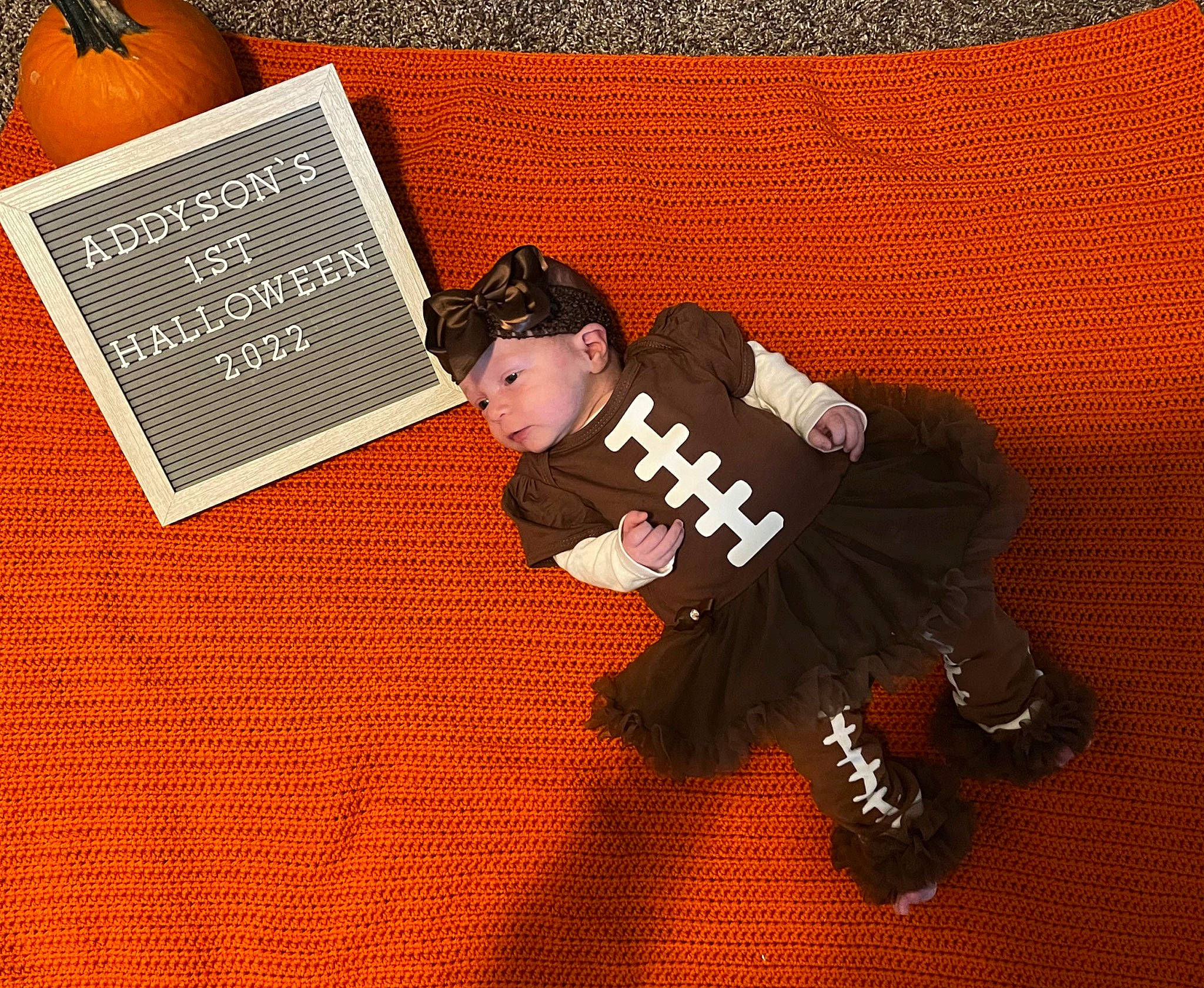 Addyson is registered to the contest to win money with this photo: baby_toddler_clothing, brand, child, flooring, font, graphics, happy, headwear, jersey, logo, natural_foods, orange, pattern, person, room, sleeve, sports_gear, sports_uniform, sportswear, t_shirt