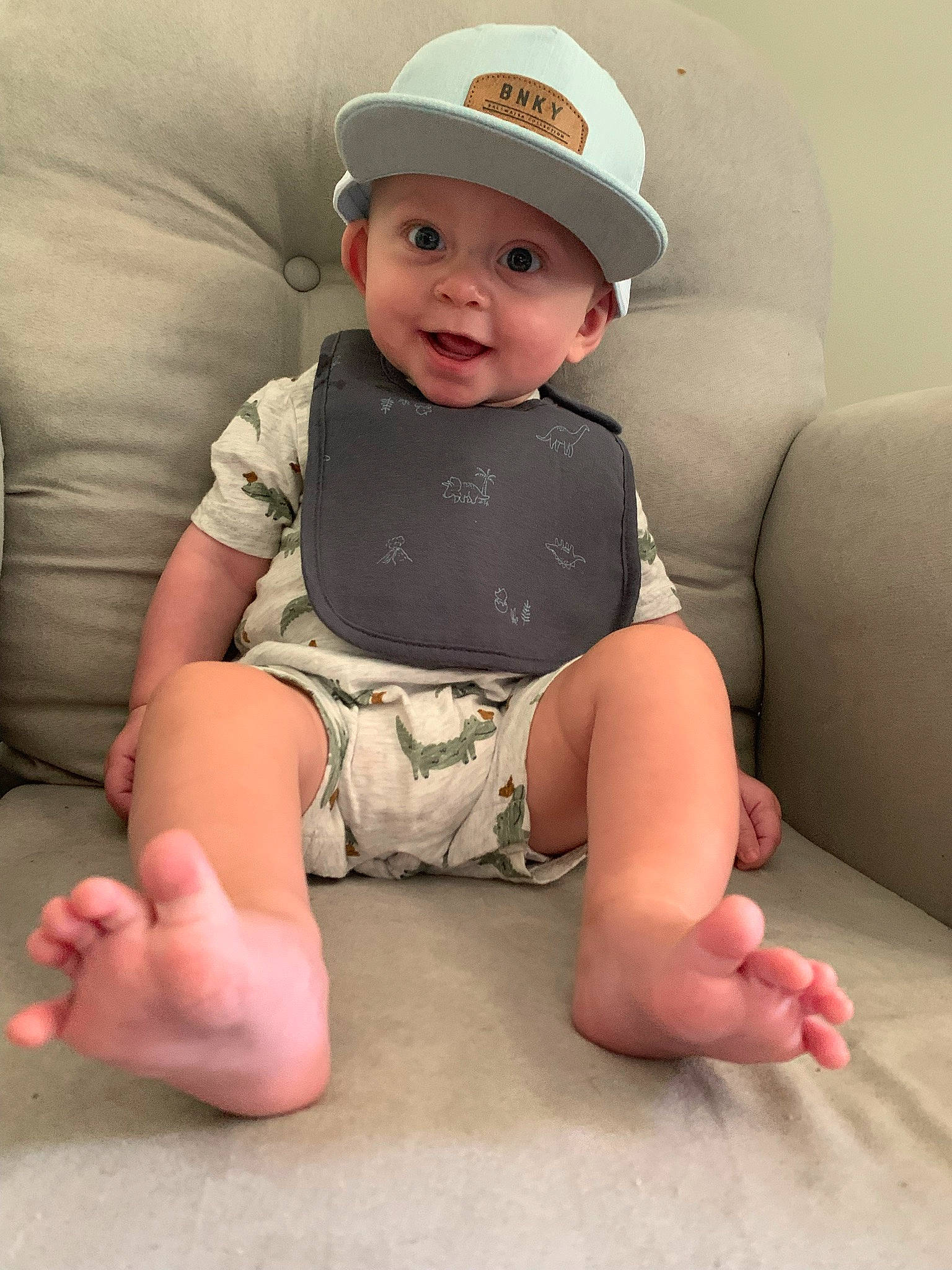 Colton is registered to the contest to win money with this photo: baby, baby_toddler_clothing, cap, comfort, eye, finger, flash_photography, headgear, headwear, human_body, knee, lip, mouth, person, pink, shoulder, skin, sleeve, smile, stomach