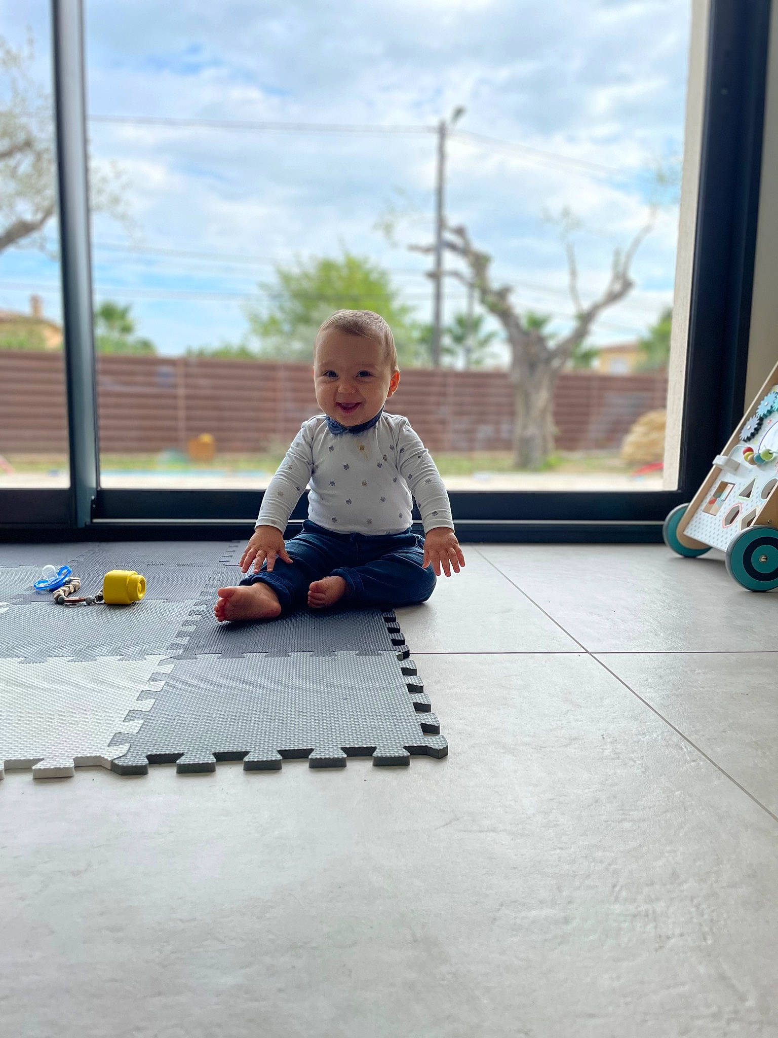 Giulian participe au concours pour gagner de l'argent avec cette photo : baby, barefoot, child, cloud, electric_blue, floor, flooring, foot, glass, hardwood, joy, leisure, person, recreation, sitting, sky, standing, t_shirt, toddler, tree