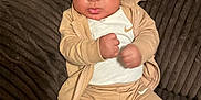 Kaiden Aka Kg is registered to the contest to win money with this photo: baby, infant, child, couch, clothing, nike, jacket, pants, socks, fist, face, curly_hair, indoor, plush_furniture, relaxed, portrait, cute, young_child, comfort, seated