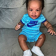 Kaiden Aka Kg is registered to the contest to win money with this photo: baby, child, sitting, nike, blue_outfit, white_sneakers, curly_hair, couch, indoor, portrait, smiling, cute, infant, clothing, footwear, person, young_child, fashion, happy, casual