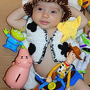 Thiago is registered to the contest to win money with this photo: baby, child, cowboy, crocheted_clothing, hat, toy_story, woody, buzz_lightyear, alien_toy, pink_piggy_bank, yellow_star, cardboard_box, cute, smiling, indoor, portrait, toy, infant, costume, playful