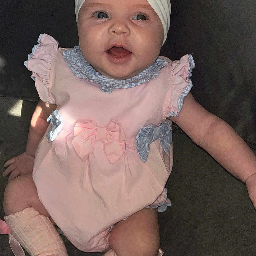 Delilah is registered to the contest to win money with this photo: accessories, baby, bonnet, cap, clothing, costume, dress, face, footwear, happy, hat, head, hosiery, newborn, person, photography, portrait, shoe, sitting, sock