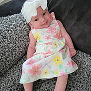 Lyra-Lily joined the competition — help win amazing prizes! baby, child, infant, smiling, headband, bow, dress, floral_pattern, sitting, blanket, couch, fabric, texture, indoors, cute, happy, person, young_child, portrait, relaxing