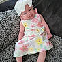 Lyra-Lily joined the competition — help win amazing prizes! baby, child, infant, smiling, headband, bow, dress, floral_pattern, sitting, blanket, couch, fabric, texture, indoors, cute, happy, person, young_child, portrait, relaxing