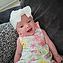 Lyra-Lily joined the competition — help win amazing prizes! baby, child, smiling, headband, bow, dress, floral_pattern, sitting, blanket, couch, indoor, happy, portrait, infant, person, cute, relaxing, cozy, natural_light, home