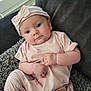 Lyra-Lily is registered to the contest to win money with this photo: baby, infant, child, headband, pink_clothing, cherry_pattern, couch, blanket, indoor, portrait, cute, face, hands, relaxed, soft_lighting, comfort, young_child, person, seated, looking_at_camera