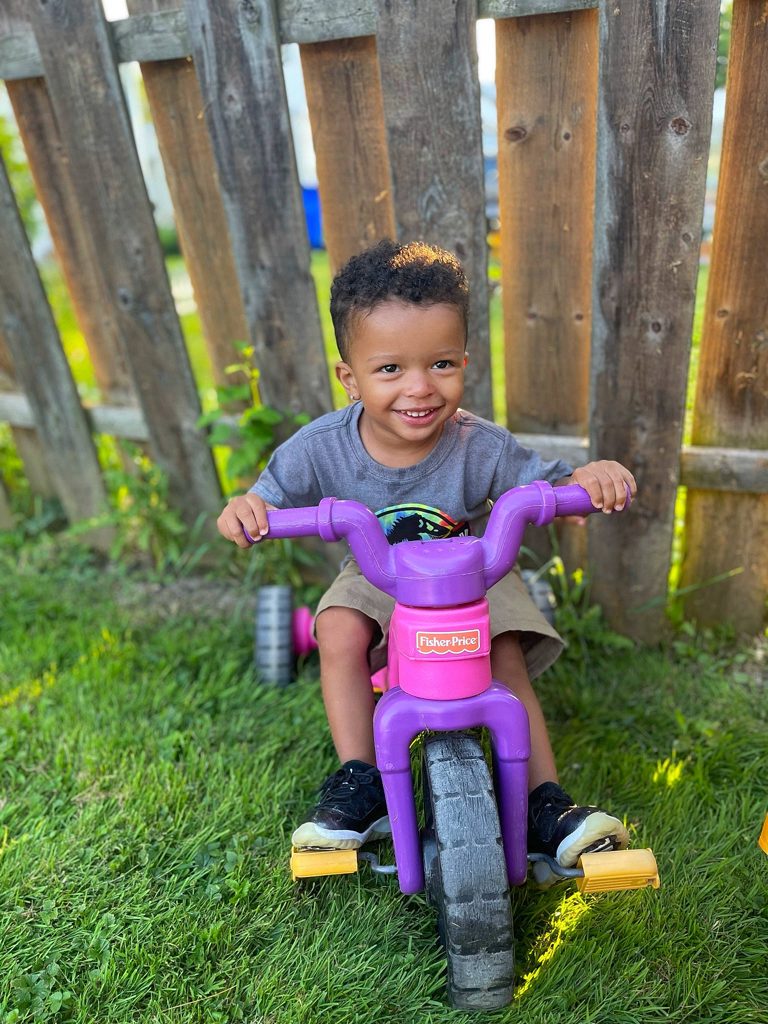Delvonte Jr is registered to the contest to win money with this photo: baby_toddler_clothing, bicycle, bicycle_accessory, child, city, fence, grass, hand, happy, joy, leisure, magenta, people_in_nature, person, plant, recreation, riding_toy, smile, tire, toddler