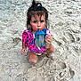 child, toddler, beach, sand, sippy_cup, floatation_vest, messy_hair, pony_tail, sitting, drinking, outdoor, play, summer, water_toy, footprints, curious, cute, sun_kissed, vacation, fun