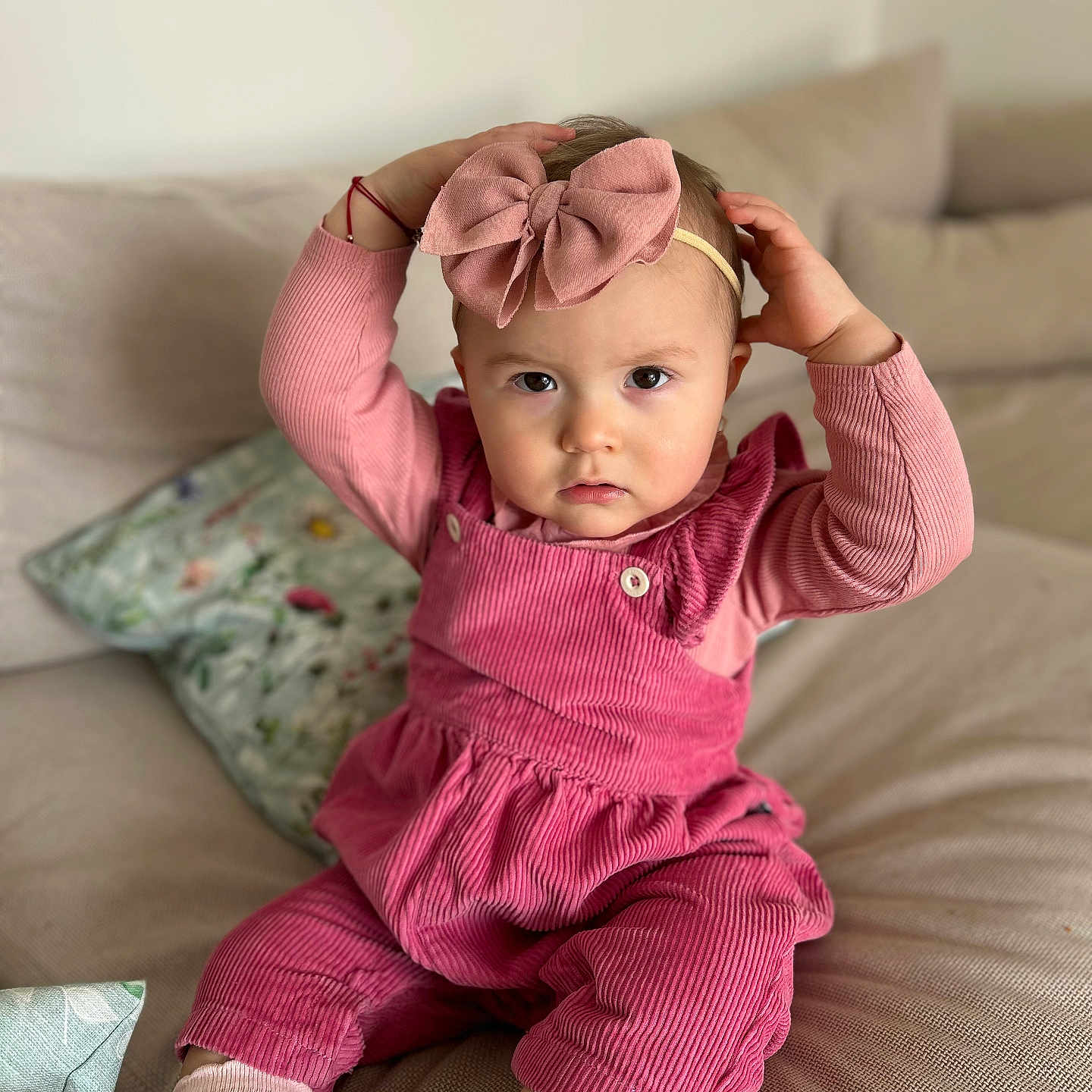 Anastassïa a rejoint le concours — aidez-le/la à gagner de superbes lots ! toddler, child, pink_bow, pink_outfit, sitting, couch, indoor, portrait, cute, baby, hands_on_head, serious_expression, cozy, headband, long_sleeves, cushion, soft_lighting, casual, home, fashion