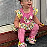 toddler, child, smiling, sitting, colorful_clothing, pink, bunny_design, snack, window, blinds, door_frame, shoes, polka_dots, hair_tie, earrings, outdoor, wooden_ledge, happy, cute, portrait