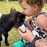 Amelia joined the competition — help win amazing prizes! toddler, baby_goat, child, animal, grass, outdoor, barn, tattoo, cup, feeding, person, clothing, blue_footwear, hand, summer, pet, cute, interaction, fun, nature